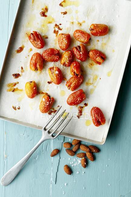 Date tomatoes sprinkled with salt and filled with almonds, on a baking sheet — Stock Photo