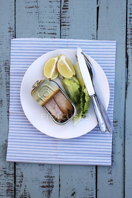 Tonno in scatola, lattuga e limone con posate sul piatto — Foto stock