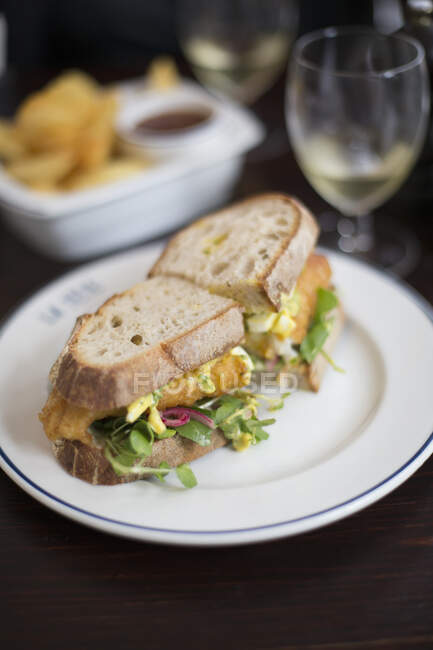Fish sandwich cut in two parts on plate — Stock Photo