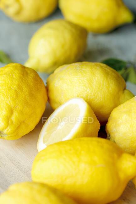 Plusieurs citrons entiers et coupés en deux (gros plan) — Photo de stock