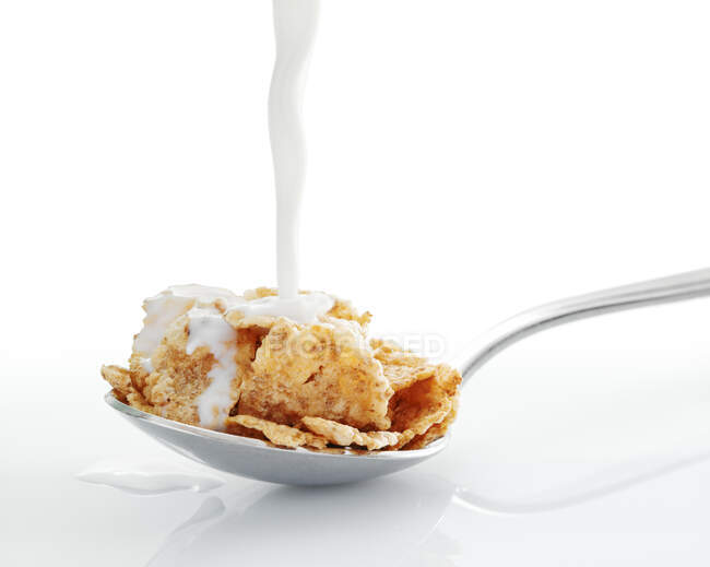 Milk being pouring on spoonful of cornflakes — Stock Photo