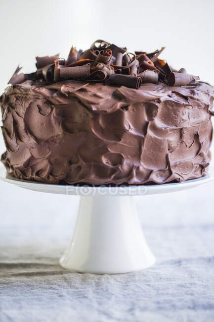 Um bolo de creme de chocolate de três camadas em uma banca de bolo — Fotografia de Stock
