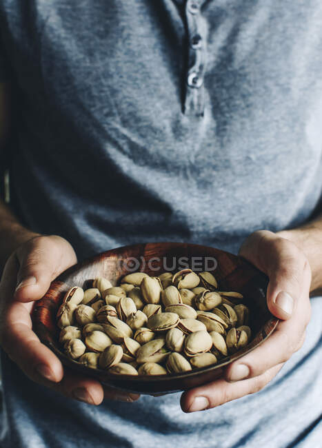 Cropped shot of person holding Bowl of pistachios — Stock Photo