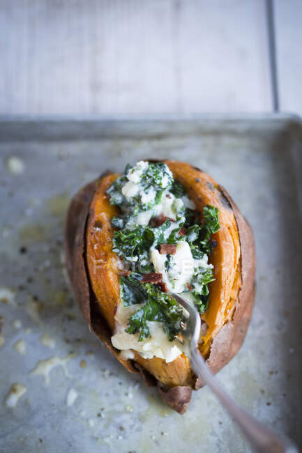 A sweet potato filled with kale, bacon and cheese — Stock Photo