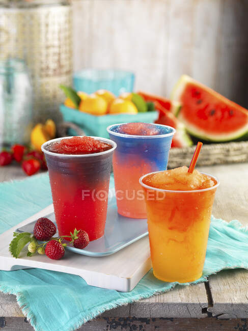 Tres lodos de frutas diferentes en vasos de plástico - foto de stock