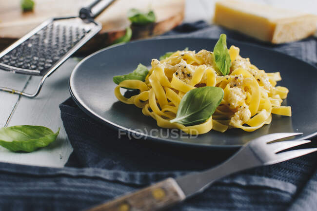 Fettuccine con salsa de parmesano y limón y hojas de albahaca fresca - foto de stock