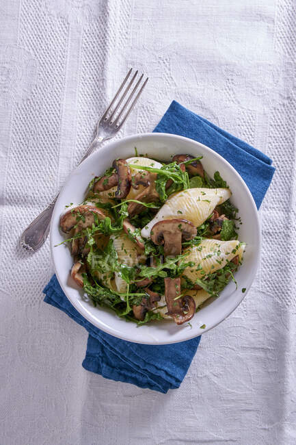 Pasta Shell con funghi e foglie di insalata rucola — Foto stock