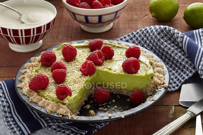 Vegan avocado and lime tart with raspberries, sliced — Stock Photo