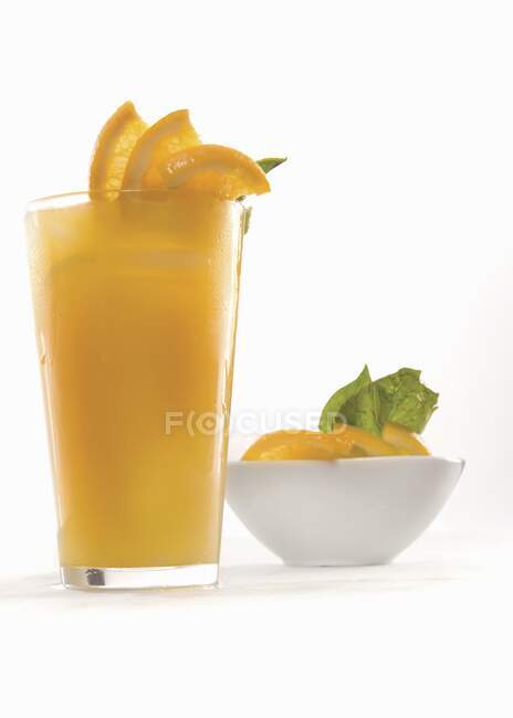Fresh orange juice garnished with orange slices and green leaves — Stock Photo