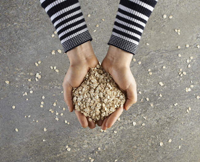 Hands holding rolled oats — Stock Photo