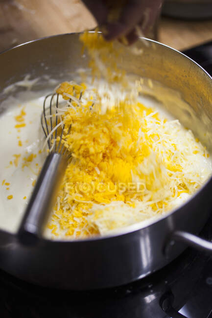 A cook preparing cheese sauce for making macaroni cheese — Stock Photo