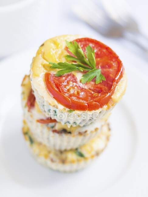 Breakfast eggs muffins with spinach, zucchini and tomatoes arranged in stack — Stock Photo