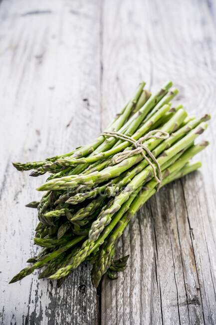 Bunch of fresh green asparagus on wooden background — Stock Photo