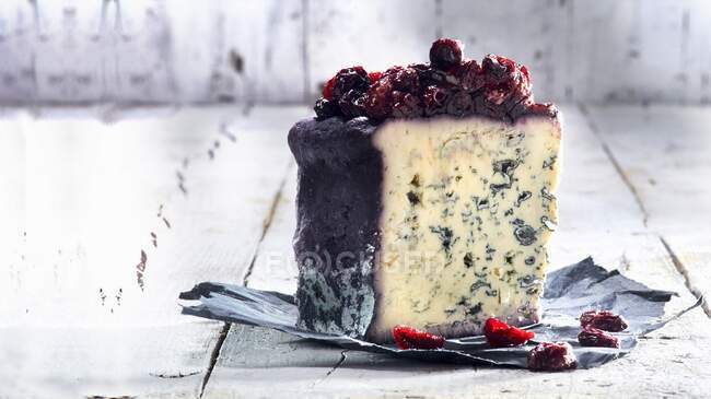 Blue cheese with cranberries served at rustic background on foil piece — Stock Photo