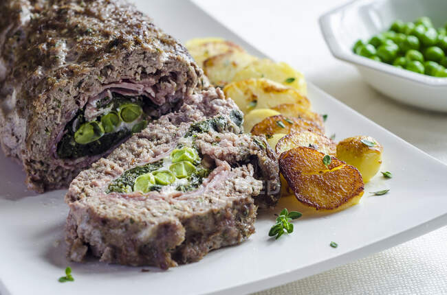 Meatloaf filled with peas and ham with fried potatoes — Stock Photo