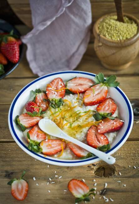 Reisbrei mit frischen Erdbeeren, Kräutern und Löffel in Schüssel — Stockfoto
