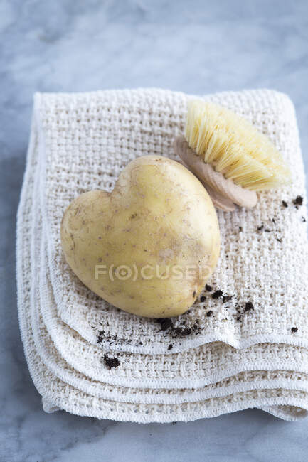 A heart shaped potato and brush on a dishcloth — Stock Photo