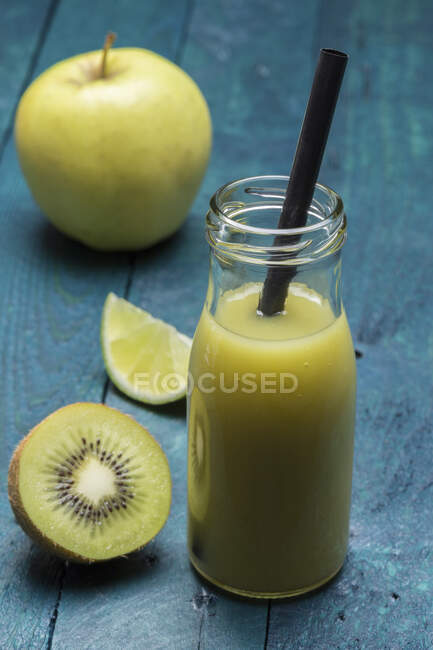 Un kiwi e un frullato di mele con lime in una bottiglia con una cannuccia — Foto stock