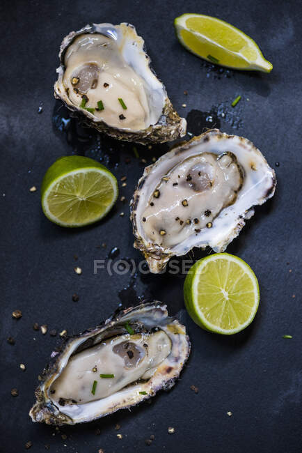 Oysters with pepper and limes — Stock Photo