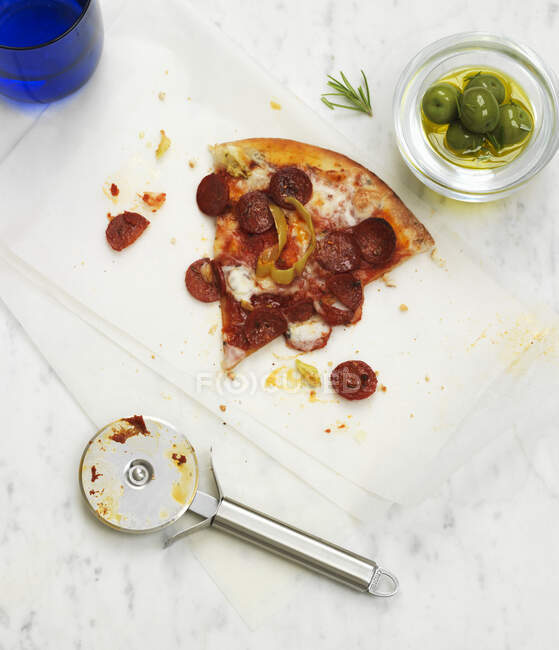 Una fetta di pizza piccante con una ciotola di olive verdi — Foto stock