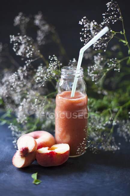 A watermelon and peach smoothie in a glass bottle with a straw — Stock Photo