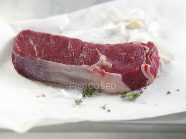 Una bistecca cruda su carta — Foto stock