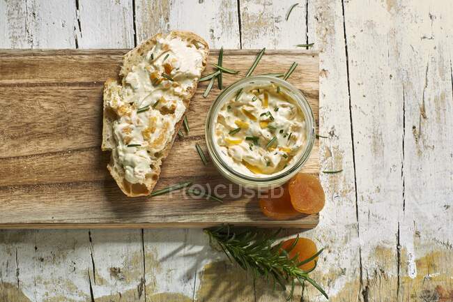 Сливочный сыр с абрикосами и розмарином в банке и на ломтике хлеба — стоковое фото