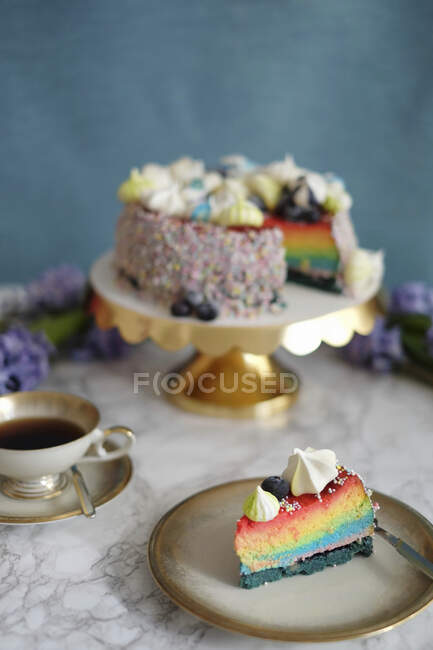 Una rebanada de pastel de queso arco iris en un plato - foto de stock