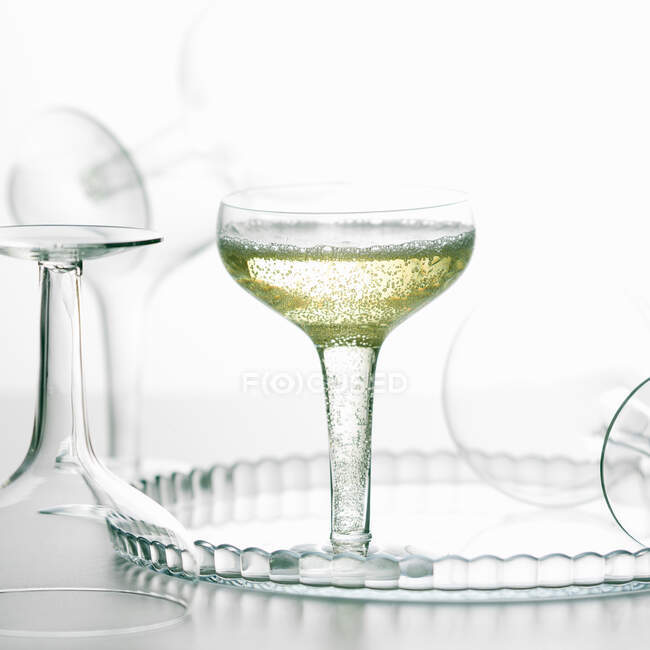 Copa de champán burbujeante bebida con vasos vacíos - foto de stock