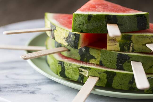 Wedges of watermelon with lollipop sticks on plate — Stock Photo