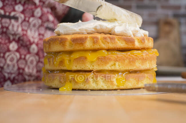 Sponge cake with lemon curd being spread with cream — Stock Photo