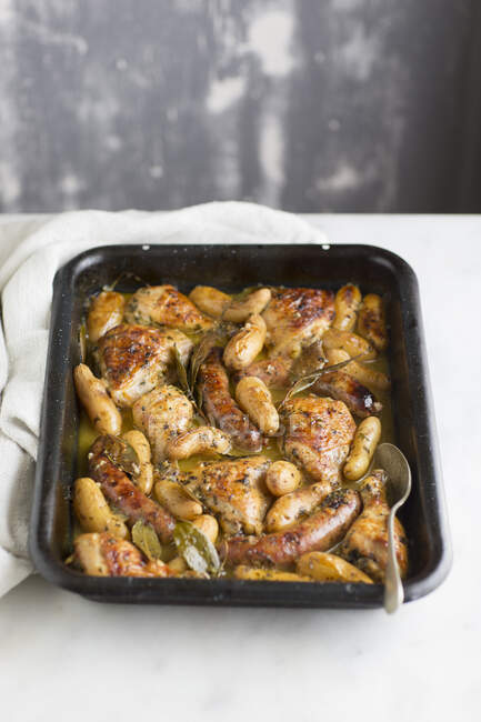 Chicken and sausage roasted in tray with white wine and bay — Stock Photo