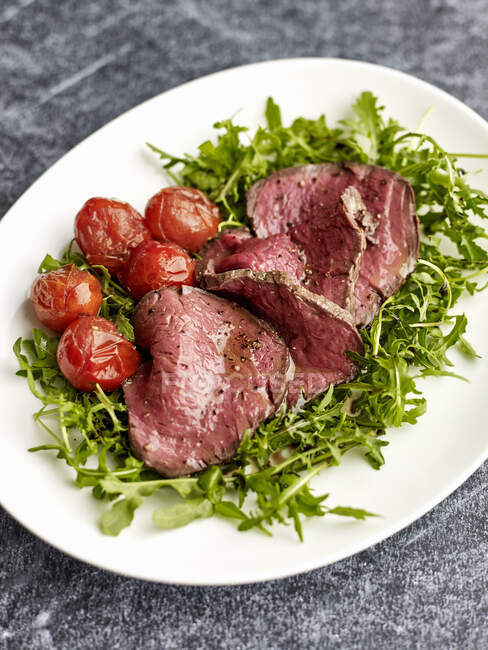 Tagliata di Manzo (beef fillet on a bed of rocket with cocktail tomatoes, Italy) — Stock Photo