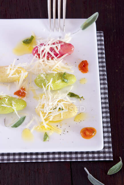 Gnocchi colorati con burro di salvia e parmigiano su un piatto di portata — Foto stock