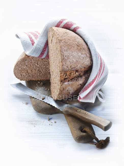 Пшеничний хліб на дошці для рубання з ножем і рушником для чаю. — стокове фото