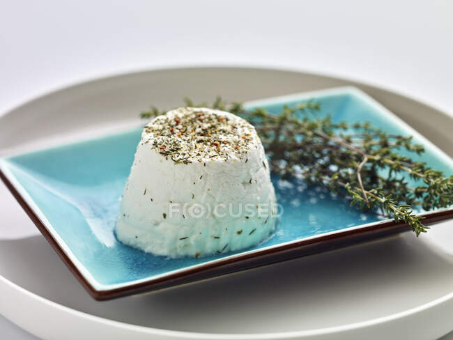 Formaggio di capra fresco con erbe aromatiche su un piatto blu — Foto stock