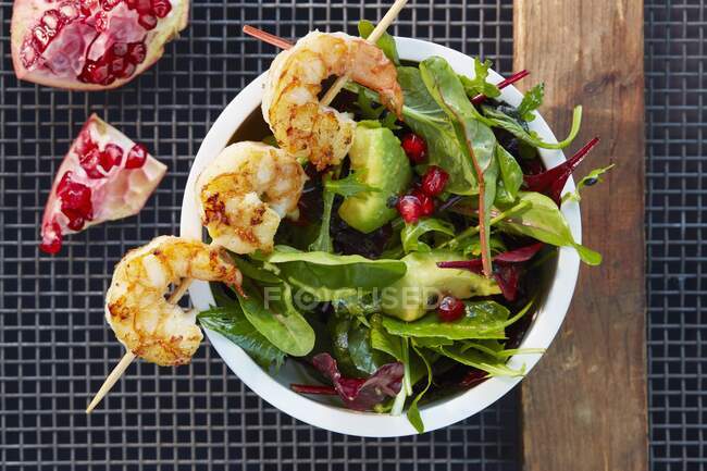 A prawn skewer on avocado salad with pomegranate seeds — Stock Photo