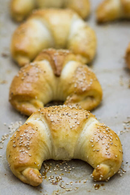 Croissant con semi di sesamo su una teglia da forno — Foto stock