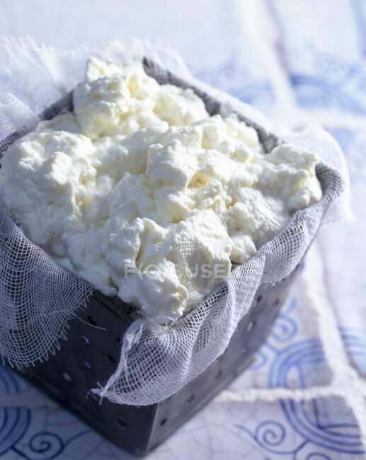 Fresh cheese on gauze cloth in container — Stock Photo