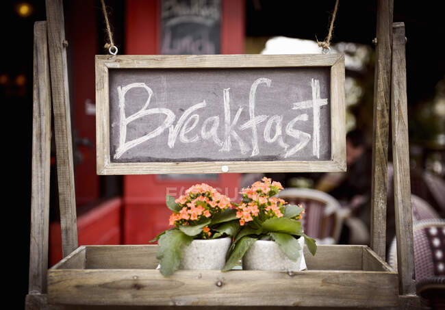 Un cartello 'colazione' con fiori su uno scaffale di legno in un ristorante — Foto stock