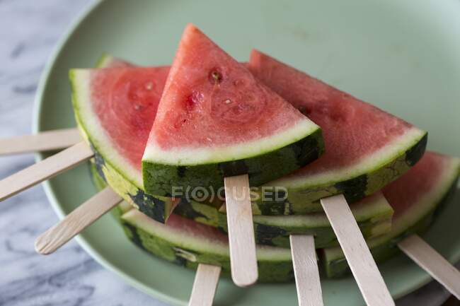 Keile aus Wassermelone mit Lutschstangen auf Teller — Stockfoto