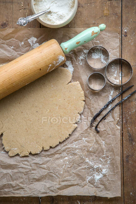 Vegan biscuit dough on baking paper with a rolling pin — Stock Photo