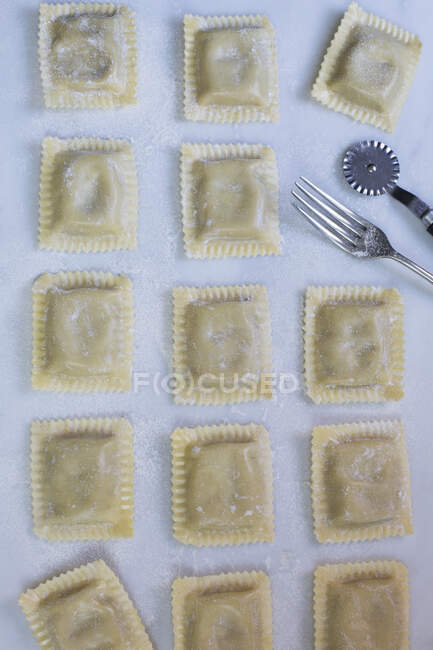 Homemade tortelloni with a fork and a pastry wheel — Stock Photo
