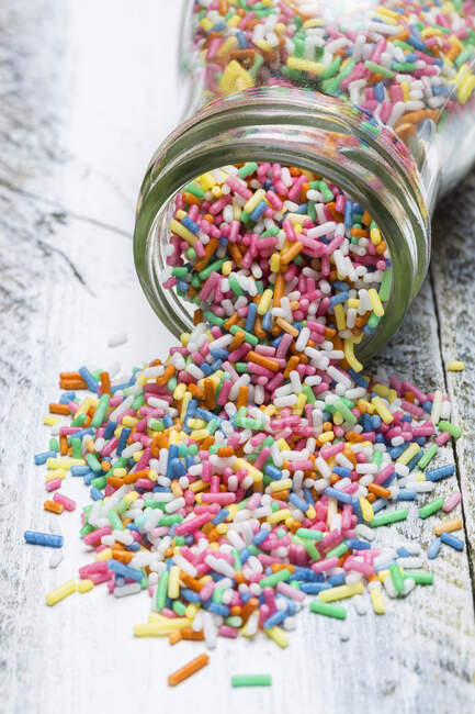 Colourful sprinkles spilling out of a jar — Stock Photo