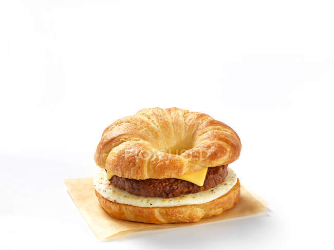 Una hamburguesa de croissant con queso y huevo sobre fondo blanco - foto de stock