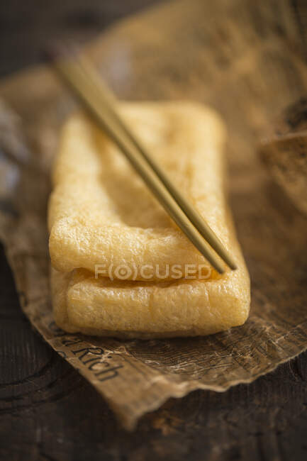Fried tofu with chopsticks on paper (Asia) — Stock Photo