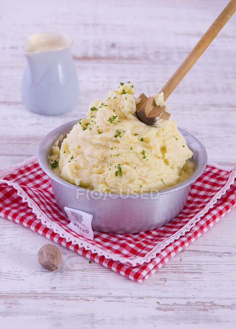 Homemade mashed potatoes in a metal bowl with a wooden masher — Stock Photo