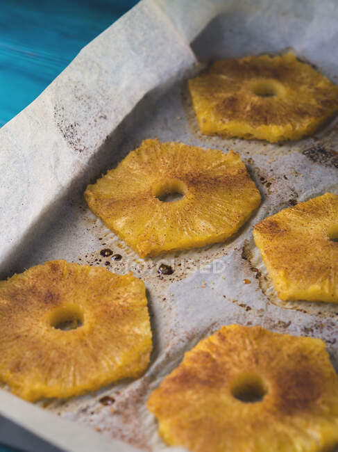 Baked ananas slices with cinnamon, Calvados liqueur and brown sugar on baking tray — Stock Photo