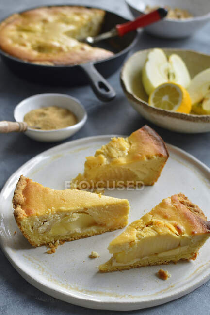 Кусочки яблочного пирога на тарелке с фруктами на заднем плане — стоковое фото