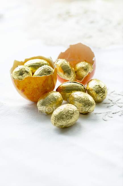 Un guscio d'uovo tinto di un uovo di Pasqua vuoto pieno di uova di cioccolato avvolto in lamina d'oro — Foto stock